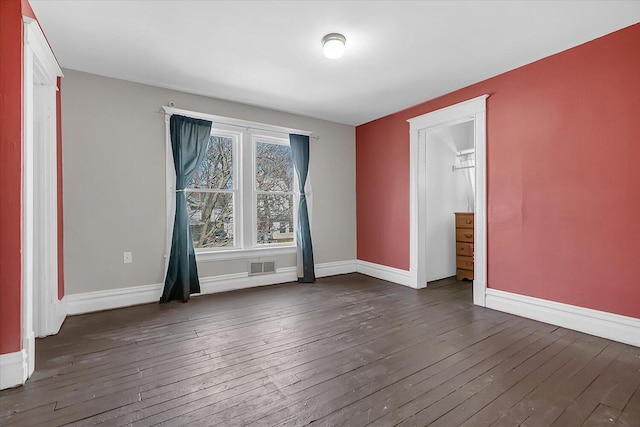 spare room featuring dark wood-style floors, visible vents, and baseboards