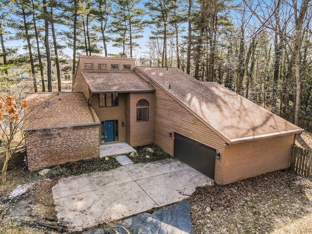 view of front of home with fence, a garage, driveway, and a shingled roof