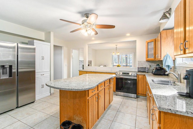 kitchen featuring light tile patterned floors, brown cabinets, stainless steel appliances, and a sink