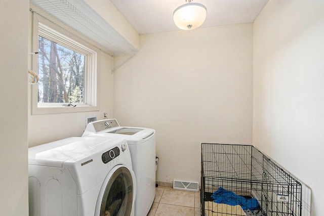 washroom featuring light tile patterned floors, baseboards, visible vents, laundry area, and washer and dryer