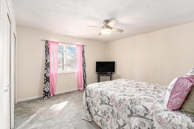 bedroom featuring visible vents, baseboards, ceiling fan, a textured ceiling, and light carpet