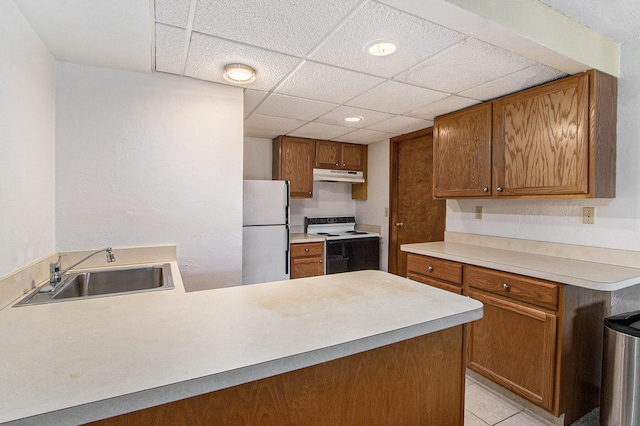 kitchen with white appliances, light countertops, under cabinet range hood, and a sink