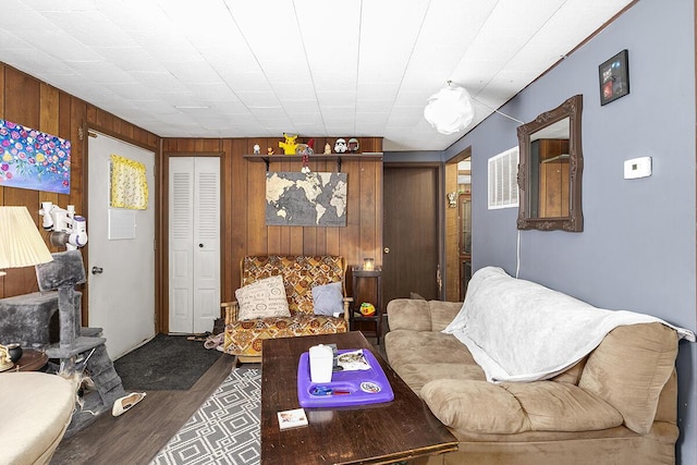 living area with wooden walls, wood finished floors, and visible vents