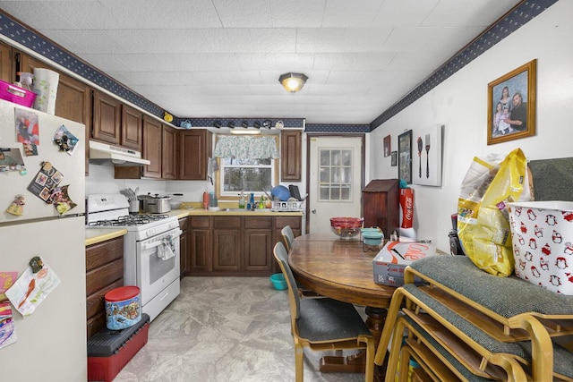 kitchen with under cabinet range hood, white appliances, and light countertops