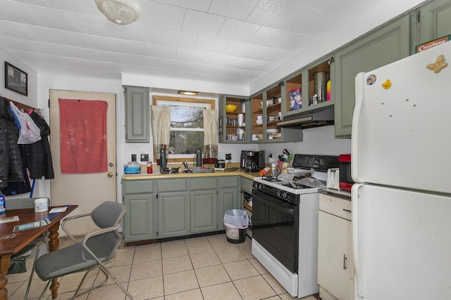 kitchen featuring under cabinet range hood, freestanding refrigerator, green cabinets, light tile patterned floors, and range