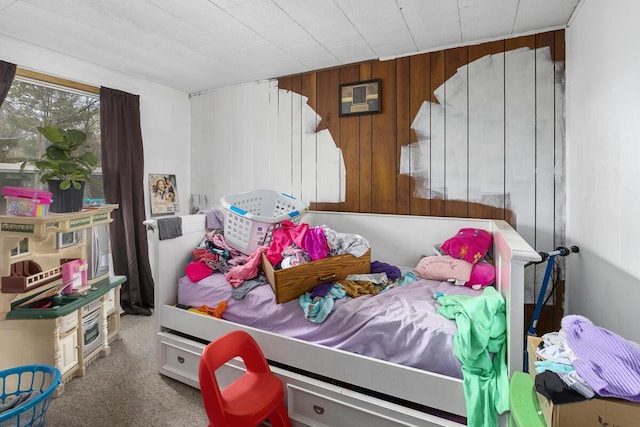 carpeted bedroom featuring wood walls