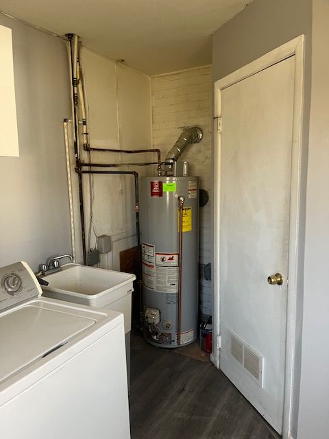 laundry area with visible vents, dark wood finished floors, water heater, laundry area, and washer / dryer