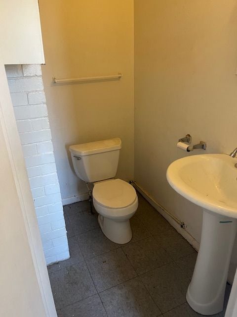 half bathroom featuring tile patterned flooring, toilet, baseboards, and a sink