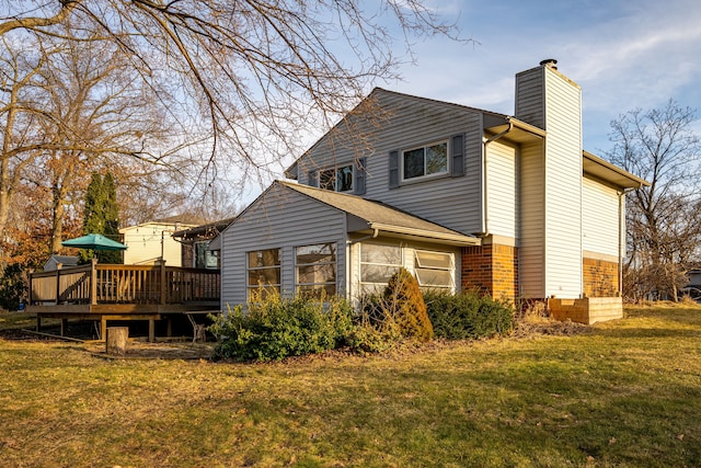 view of side of property with a deck, a yard, brick siding, and a chimney