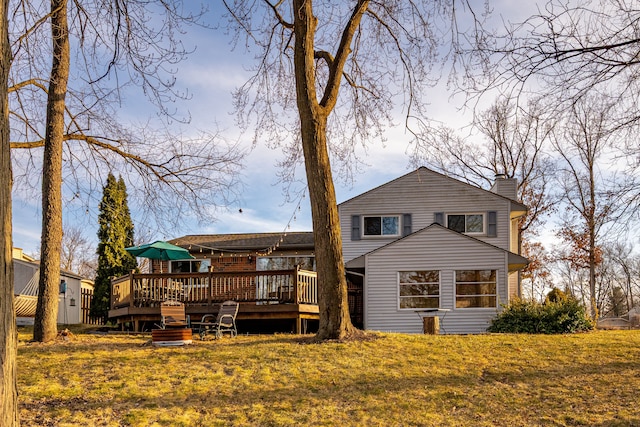 back of property featuring a yard, a chimney, and a deck