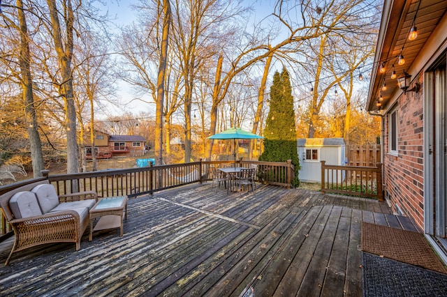 deck with outdoor dining space, a storage unit, and an outdoor structure