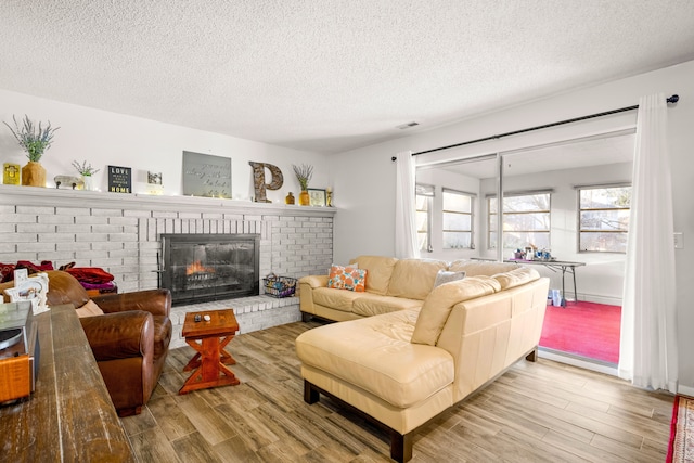 living room with light wood finished floors, plenty of natural light, and a brick fireplace