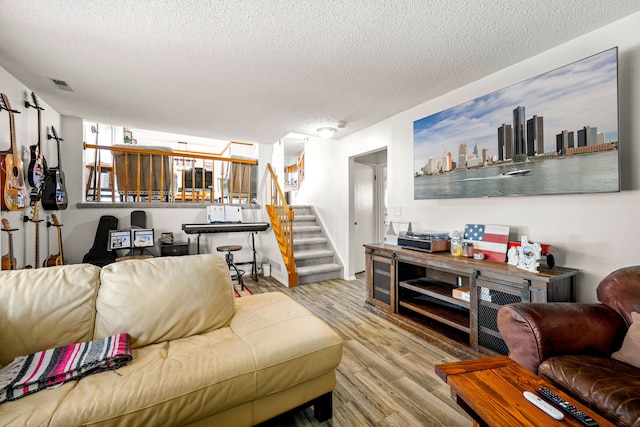 living area with visible vents, a textured ceiling, stairs, and wood finished floors