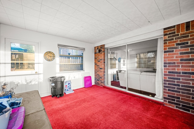 interior space featuring brick wall and carpet flooring