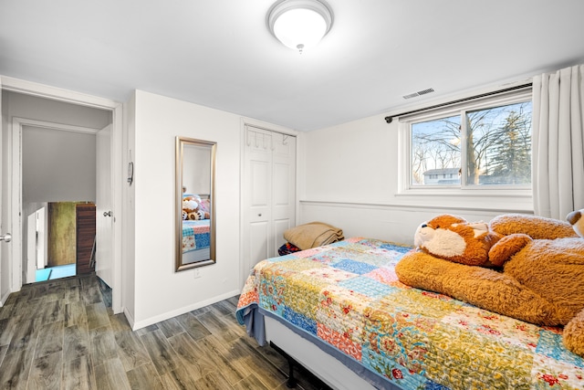 bedroom with wood finished floors, visible vents, a closet, and baseboards