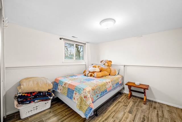 bedroom with baseboards, visible vents, and wood tiled floor