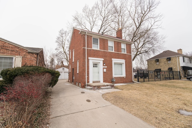 colonial home with fence, an outdoor structure, a garage, brick siding, and a chimney