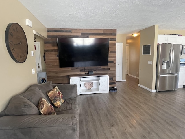 living area with visible vents, a textured ceiling, baseboards, and wood finished floors