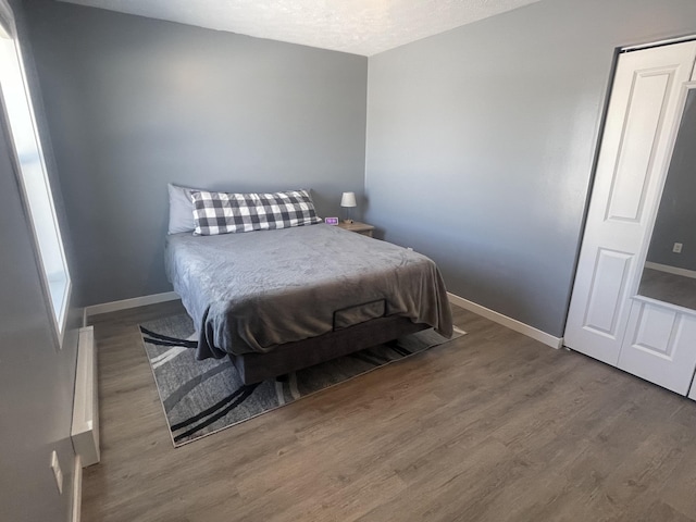 bedroom featuring baseboards, a textured ceiling, and wood finished floors