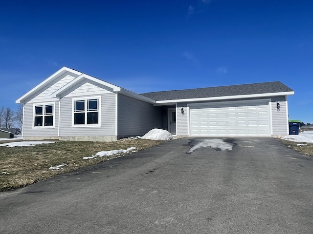 view of front facade with aphalt driveway, a shingled roof, and a garage