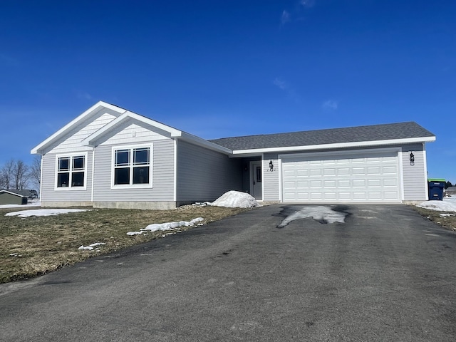 single story home featuring driveway, roof with shingles, and an attached garage