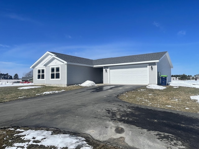 view of front of house featuring aphalt driveway, roof with shingles, and an attached garage