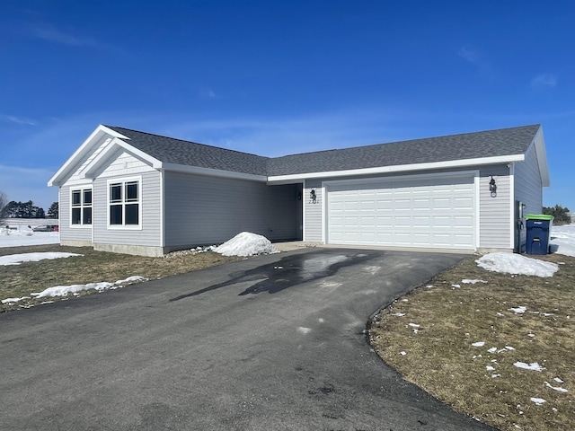 ranch-style home featuring a garage, driveway, and a shingled roof