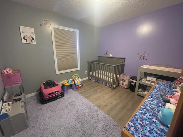 bedroom featuring wood finished floors, baseboards, and a textured ceiling