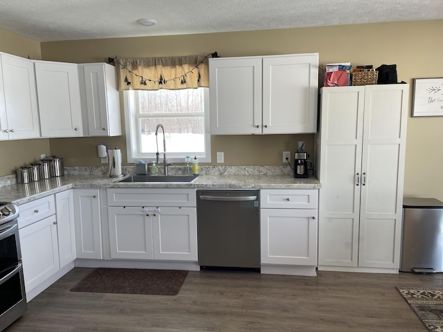 kitchen with a sink, appliances with stainless steel finishes, white cabinets, and dark wood finished floors