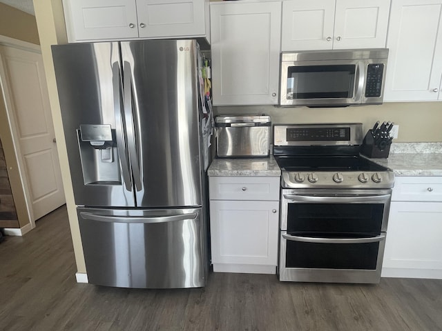 kitchen featuring light stone counters, white cabinetry, stainless steel appliances, and dark wood-style flooring