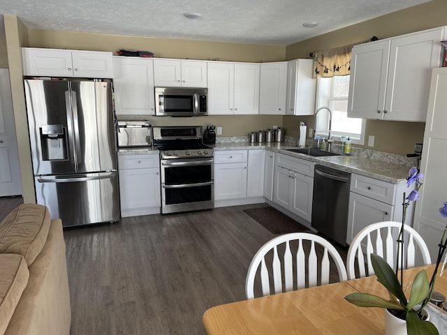 kitchen with white cabinetry, dark wood-style flooring, appliances with stainless steel finishes, and a sink