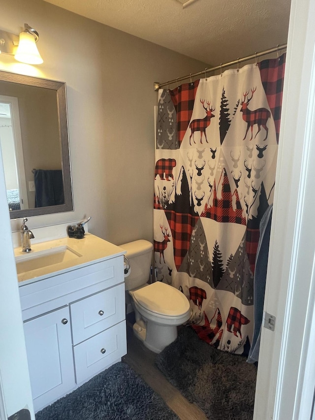 full bath with a shower with curtain, toilet, a textured ceiling, wood finished floors, and vanity