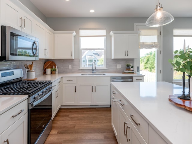 kitchen with a sink, light countertops, appliances with stainless steel finishes, white cabinetry, and tasteful backsplash