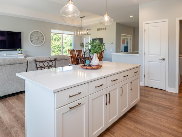 kitchen with light countertops, white cabinets, light wood-style floors, and open floor plan