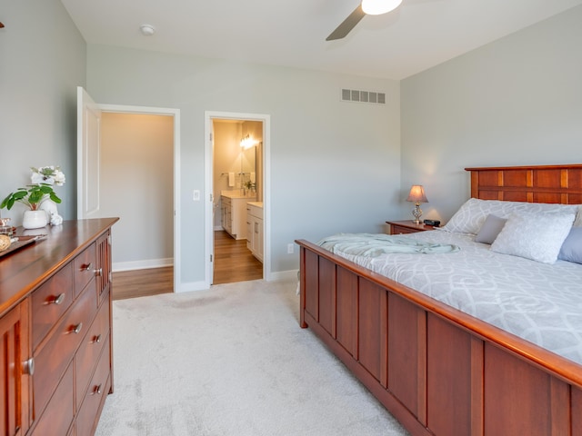 bedroom with visible vents, connected bathroom, baseboards, ceiling fan, and light colored carpet