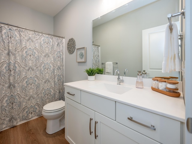 bathroom featuring toilet, vanity, and wood finished floors