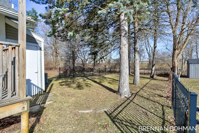 view of yard featuring a storage shed, a fenced backyard, and an outbuilding