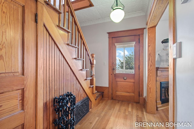 foyer entrance featuring stairs, crown molding, and light wood-style floors