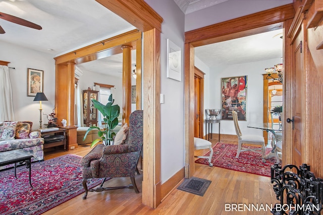 interior space featuring visible vents, baseboards, decorative columns, wood finished floors, and a ceiling fan