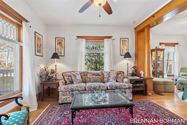 living room featuring decorative columns, wood finished floors, and ceiling fan