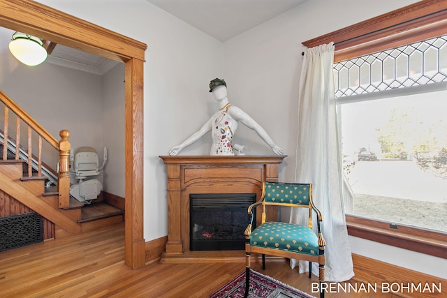 living area featuring a wealth of natural light, stairway, a glass covered fireplace, and wood finished floors