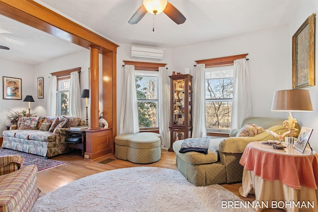 interior space featuring a wall unit AC, wood finished floors, and a ceiling fan