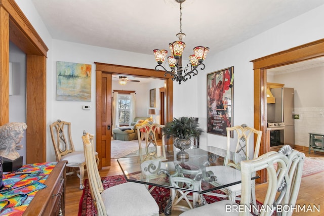 dining area featuring wood finished floors and ceiling fan with notable chandelier