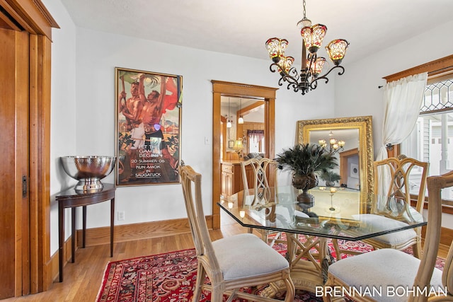 dining area featuring an inviting chandelier, wood finished floors, and baseboards