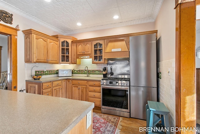 kitchen featuring a sink, an ornate ceiling, stainless steel appliances, glass insert cabinets, and custom exhaust hood