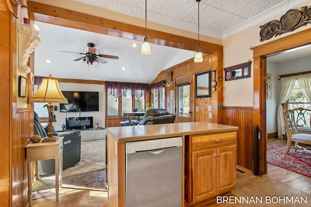 kitchen featuring a wainscoted wall, stainless steel dishwasher, hardwood / wood-style floors, wooden walls, and a brick fireplace