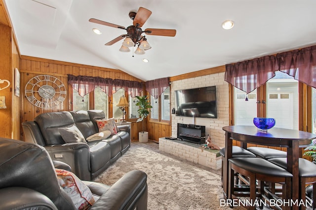 carpeted living room with wood walls, a ceiling fan, lofted ceiling, and a healthy amount of sunlight