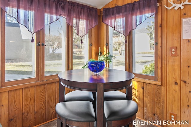 dining area featuring a healthy amount of sunlight and wood walls