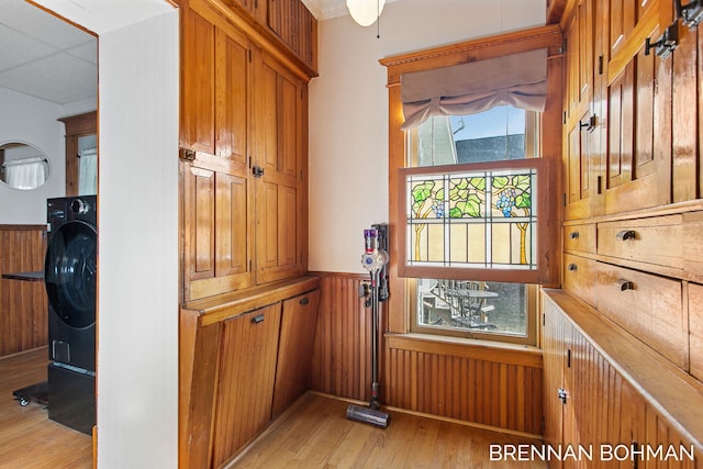 room details featuring wooden walls, washer / clothes dryer, wood finished floors, and wainscoting