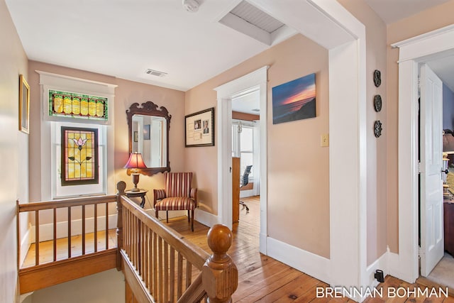 hallway featuring visible vents, light wood-style flooring, and baseboards